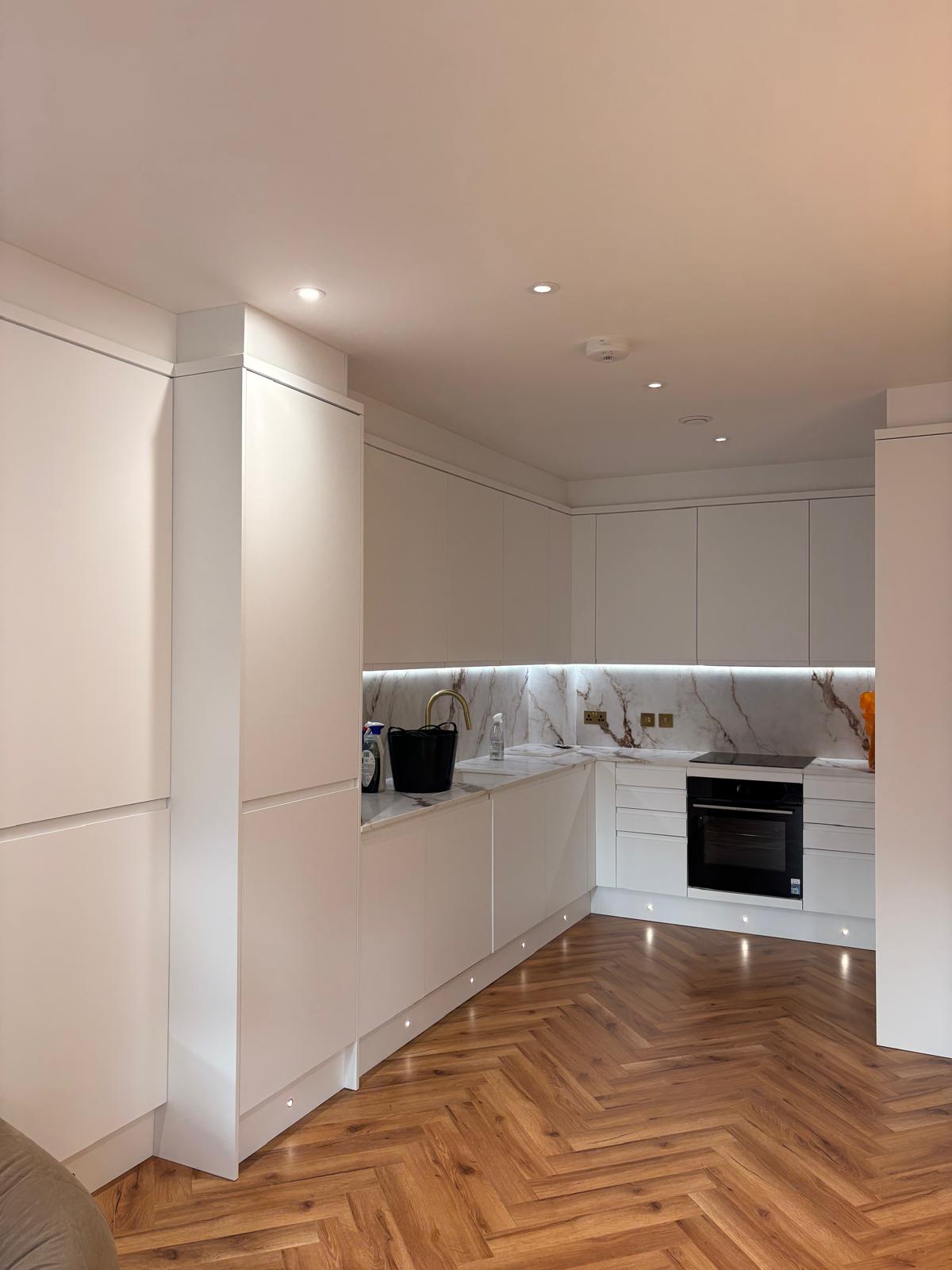 Handleless white kitchen with marble worktop and splashback