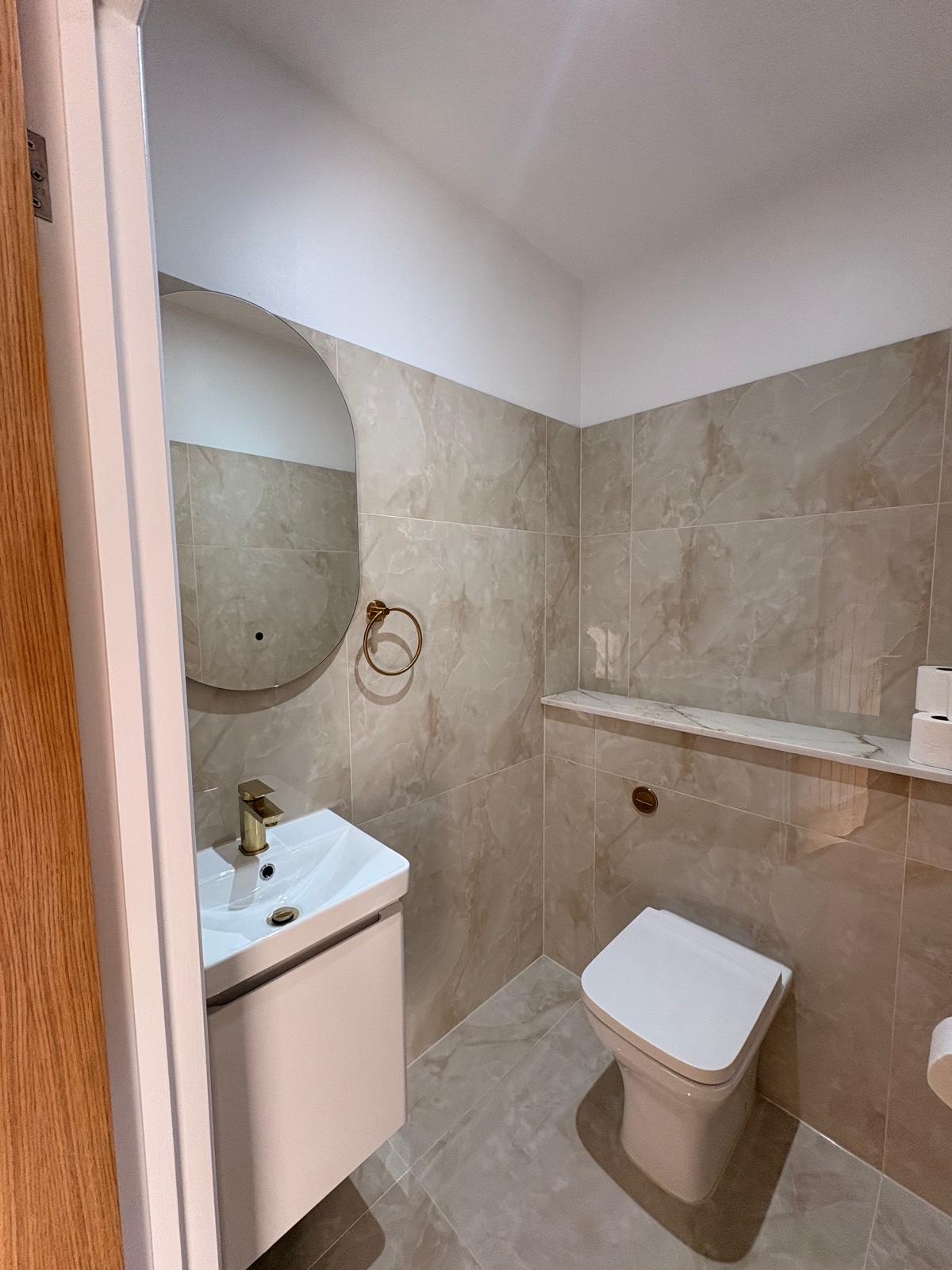 Guest WC with marble-effect tiling and brass fittings